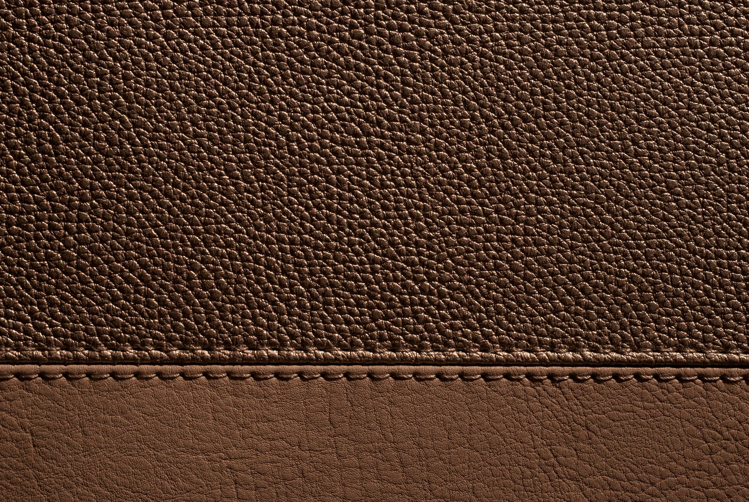 Close-up of brown pebbled leather with stitching detail.
