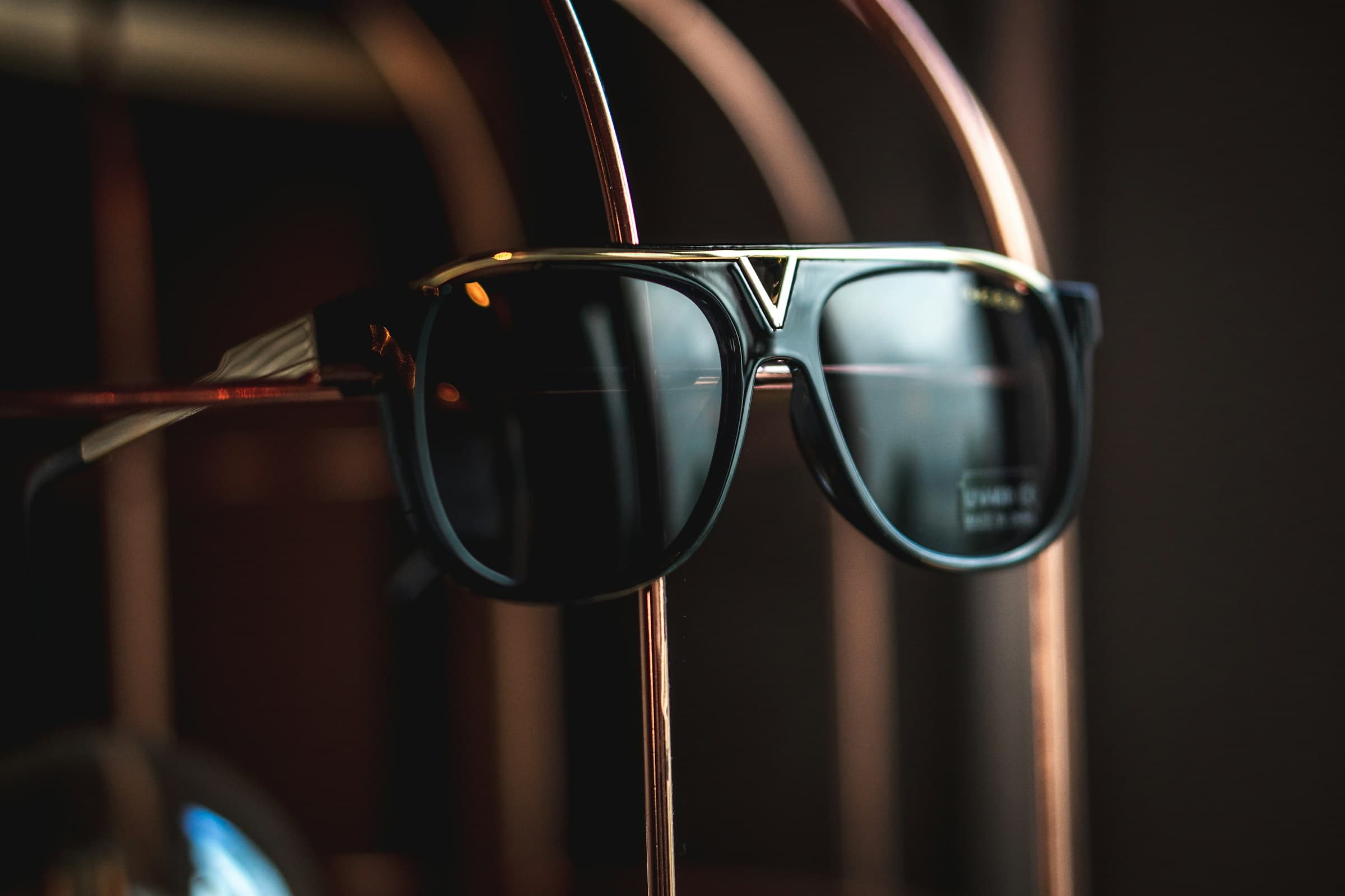 Dark sunglasses on a stand with warm reflections.